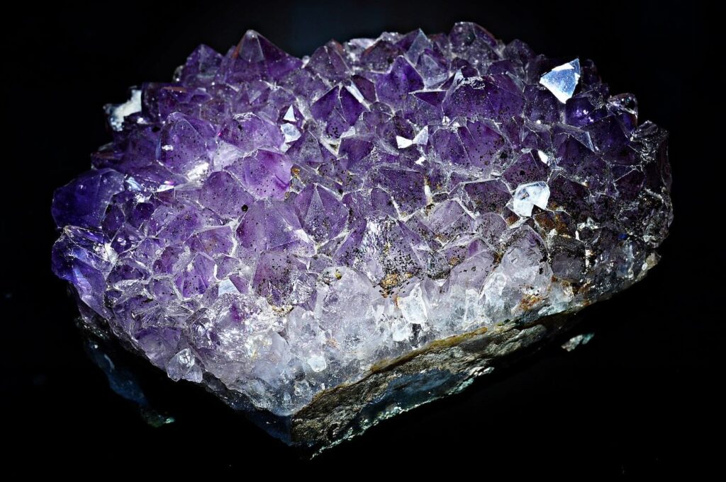 Violetter Amethyst-Kristall mit spitzen Kristallspitzen auf dunklem Hintergrund