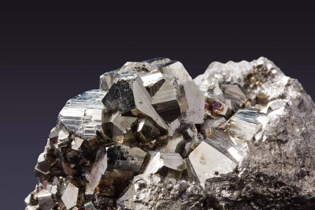 Goldglänzender Pyrit-Kristallcluster mit würfelförmiger Struktur auf dunklem Hintergrund